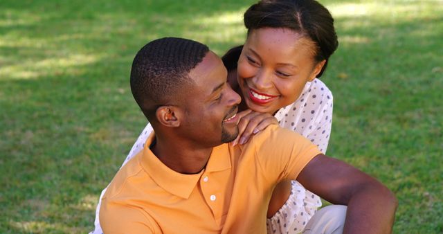 A young African American couple enjoys a romantic moment outdoors, with copy space. Their affectionate embrace and joyful expressions convey a sense of love and happiness.