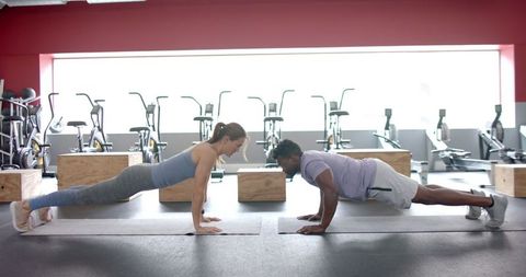 Diverse Gym Duo in Plank Position Highlighting Core Strength Devotion
