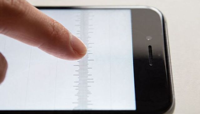 Fingertip pressing smartphone touchscreen over ruler scale closeup for calibration testing