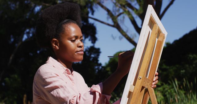 African american woman painting picture on canvas in sunny garden - Download Free Stock Photos Pikwizard.com
