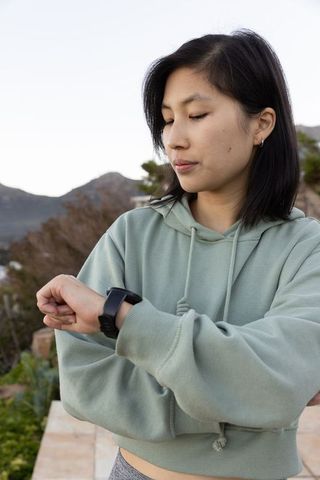 Woman Wearing Smartwatch Relaxing Outdoors on Scenic Terrace