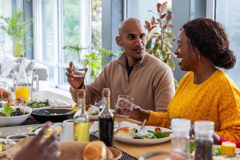 Sharing laughter over lunch: midlife diverse couple dining together in bright modern home