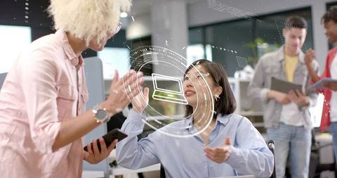 Diverse team collaborating around holographic laptop interface in modern open office