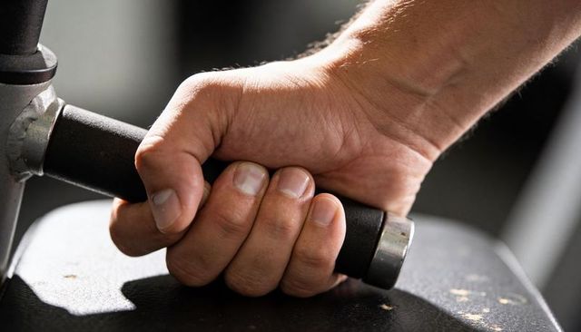 Closeup right hand gripping gym machine handle for strength training and workout focus