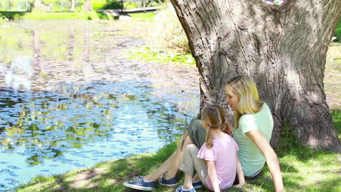 Mother and Daughter Relaxing by Peaceful River