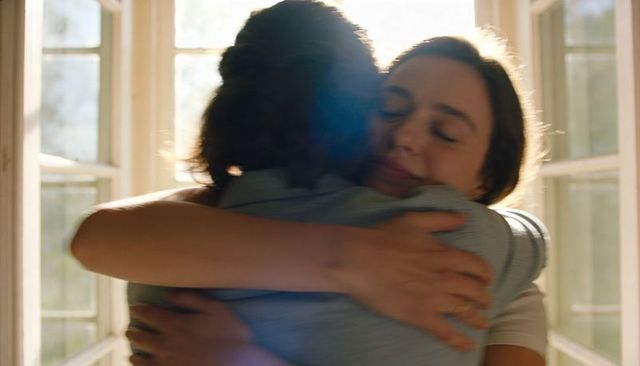 Sunlit home embrace showing couple hugging with ring, intimacy, warm backlight and lens flare