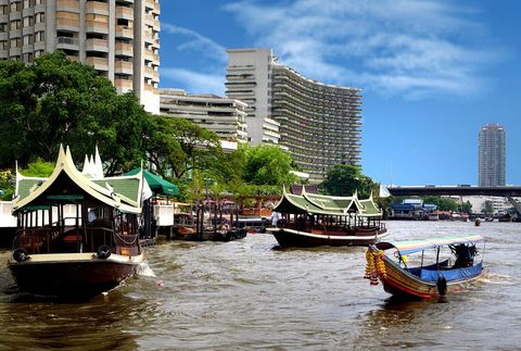 Traditional Boats Navigating Bustling River with Modern Skyline
