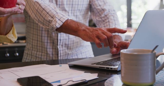 Hand Pointing at Laptop Screen in Kitchen Workspace - Download Free Stock Images Pikwizard.com