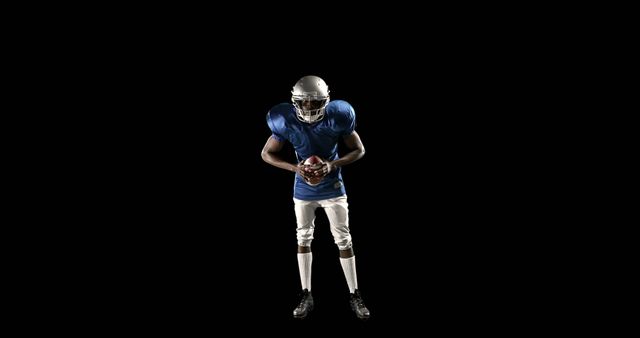 American football player in uniform holding ball against black background - Download Free Stock Images Pikwizard.com