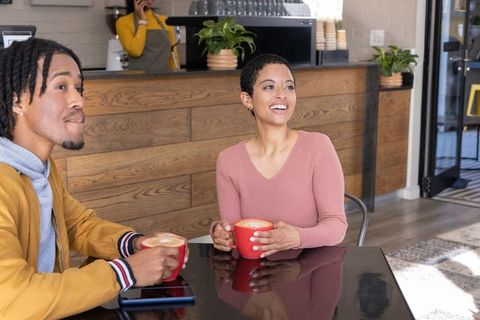 African american couple enjoying lattes and laughing in cozy wood coffeehouse