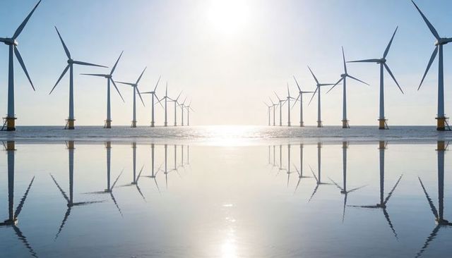 Offshore turbine row generating clean energy with mirrored rotor reflection on calm sea