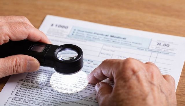 Senior hands using illuminated magnifier for reading medical form and small print