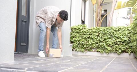 Person Handling Delivered Package Near Residential Front Door