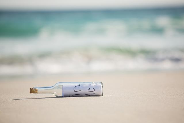 Message in a bottle lying on sandy beach near ocean waves. Perfect for themes related to adventure, romance, mystery, travel, and communication. Ideal for websites, blogs, and marketing materials focusing on serene coastal scenes, inspiration, and storytelling.