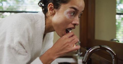 Woman enjoying morning routine brushing teeth in modern bathroom