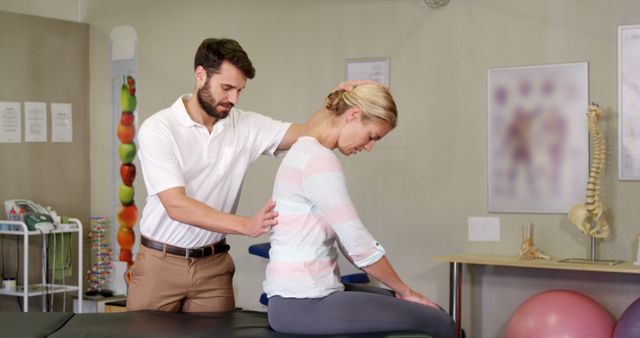 A male physical therapist is assessing the posture of a female patient in a clinic. Ideal for use in health, medical, or rehabilitation articles, websites, and brochures. Highlights health services, professional care, and patient rehabilitation.
