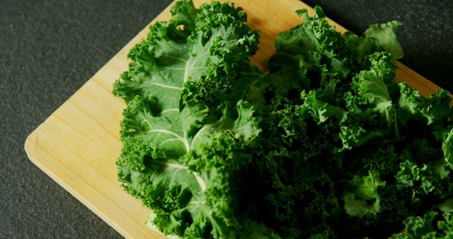 Fresh kale leaves are displayed on a wooden cutting board, with copy space. Kale is known for its nutritional benefits and is a popular ingredient in healthy diets.
