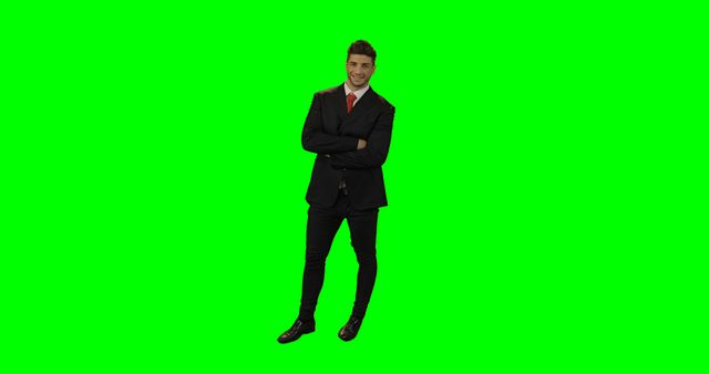 Young businessman in professional attire standing confidently with arms crossed on green screen. Ideal for use in business presentations, promotional materials, corporate training, and marketing campaigns. Easily customizable background due to green screen, making it versatile for creative projects.