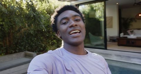 Young Man Taking Selfie by Home Pool with Open Glass Door