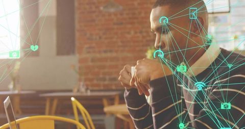 Working in cafe drinking coffee while focusing on laptop with digital network overlay