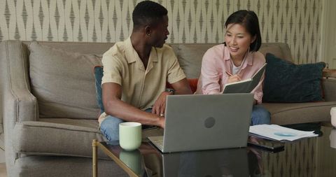 Multiethnic Team Collaborating on Couch with Laptop and Documents