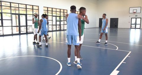 Basketball Teammates Shaking Hands on Indoor Court During Practice Game