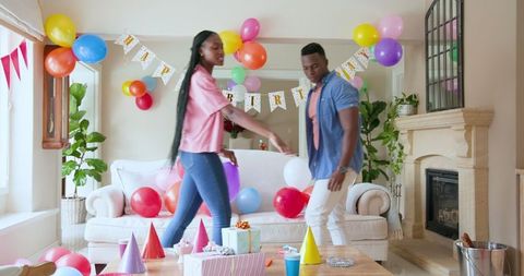 Couple Decorating Home with Balloons for Child's Birthday Celebration