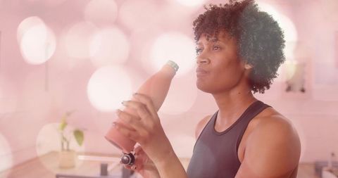 Opening matte pink bottle in home kitchen by athletic woman preparing refreshing beverage