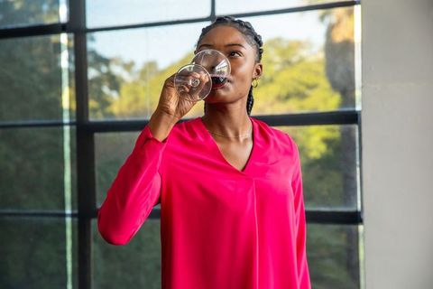 Elegant Woman in Pink Blouse Sipping Wine by Window