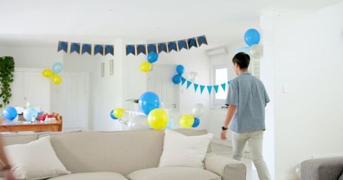 Man Decorating Living Room with Balloons for Birthday Celebration