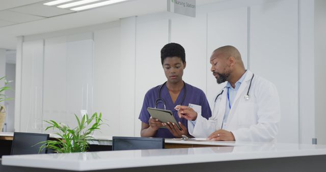 Doctors consulting at a hospital nursing station, reviewing patient prescription together. Could be used in medical publications, healthcare websites, hospital promotional materials, or educational content highlighting professional collaboration in healthcare settings.