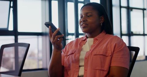 African american woman using smartphone voice assistant during modern office meeting