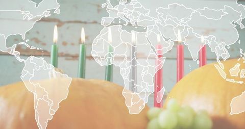 Celebrating kwanzaa with kinara, lit candles and pumpkins on turquoise rustic plank with world map