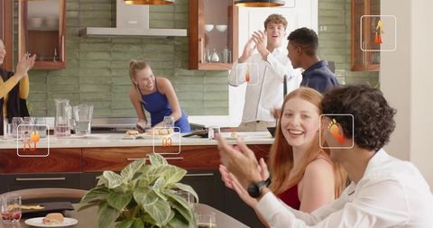 Friends clapping and laughing around modern kitchen island during casual home gathering