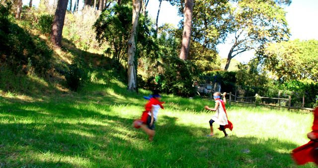 Children dressed in colorful superhero costumes eagerly running around in a grassy outdoor area. Trees and bushes surrounding the space. Perfect for use in promoting fun activities for kids, children's events, outdoor adventures, and fostering creativity and imagination in children.