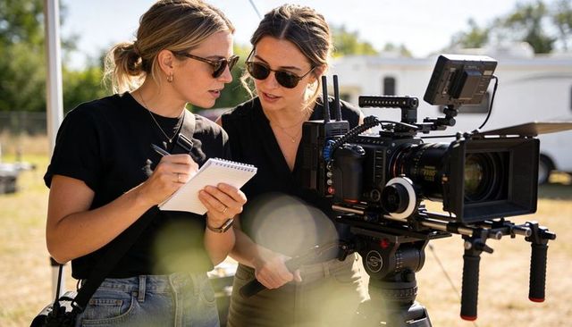 Female film crew collaborating on outdoor camera setup, director and camera operator