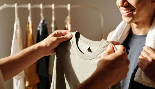 Boutique assistant holding crewneck tee while smiling customer choosing casual wardrobe
