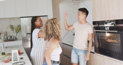 Joyful Friends High-Fiving in Modern Kitchen Gathering