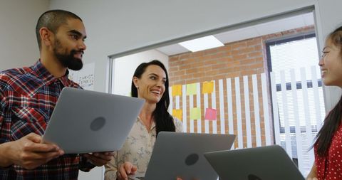 Diverse team collaborating in office with laptops
