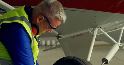 Engineer Inspecting Aircraft Landing Gear for Safety at Hangar