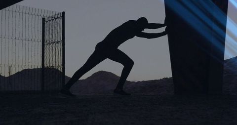 Silhouette Athlete Pushing Training Sled on Sand Dunes
