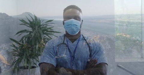 Clinician standing arms crossed wearing mask and stethoscope, double exposure coastal view
