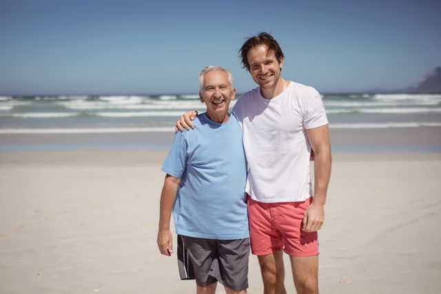 Father and son enjoying a sunny day at the beach, standing together and smiling. Ideal for use in advertisements, travel brochures, family-oriented content, and lifestyle blogs. Perfect for promoting family vacations, outdoor activities, and summer fun.