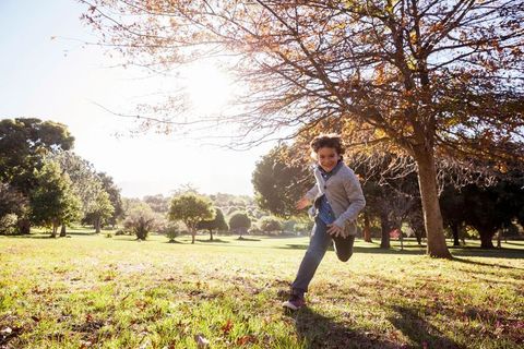 Joyful Child Running Through Sunlit Park in Autumn