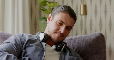 Man relaxing at home with tablet and headphones on couch