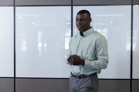 Confident Businessman Presenting in Modern Office With Glass Whiteboard