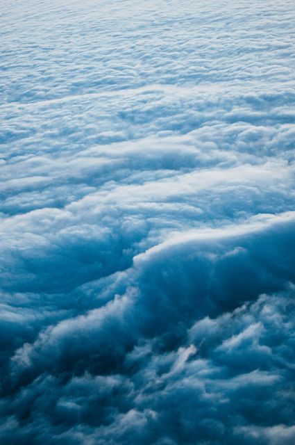Aerial view of beautiful cloudscape during sunrise, featuring fluffy clouds rolling over the horizon. Perfect for backgrounds, weather-related content, travel promotions, nature documentaries, and inspirational posters.