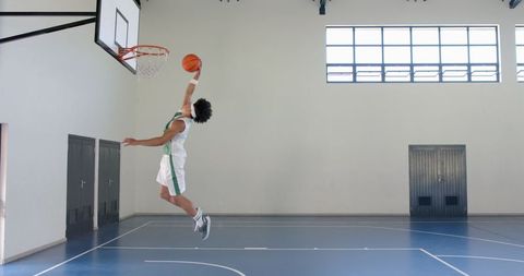 Young Athlete Dunking Basketball in Indoor Court