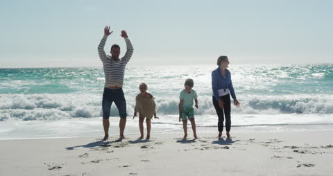 Family Enjoying Beach Fun and Jumping Waves Together