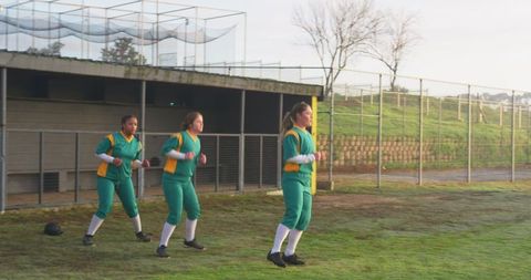 Female Softball Teammates Warming Up on Grassy Field